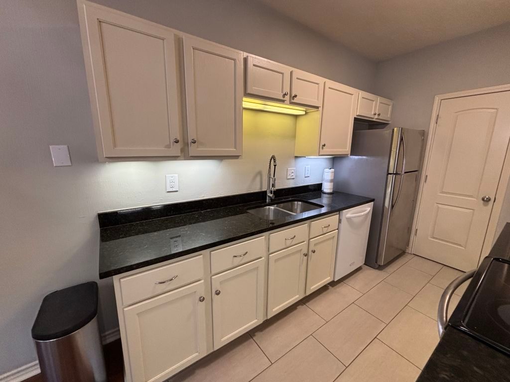 307 Quarry Street San Marcos, TX 78666 - Photo 11 of 38 Kitchen featuring black range oven, dishwasher, dark stone counters, light tile patterned floors, and freestanding refrigerator