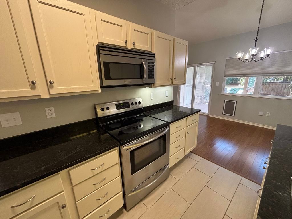 307 Quarry Street San Marcos, TX 78666 - Photo 12 of 38 Kitchen with stainless steel appliances, dark stone counters, decorative light fixtures, and light tile patterned floors