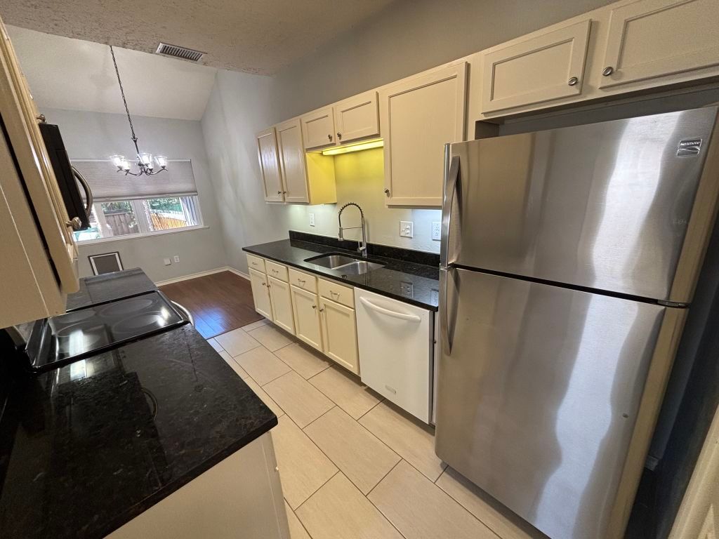 307 Quarry Street San Marcos, TX 78666 - Photo 13 of 38 Kitchen with freestanding refrigerator, white dishwasher, lofted ceiling, hanging light fixtures, and a chandelier