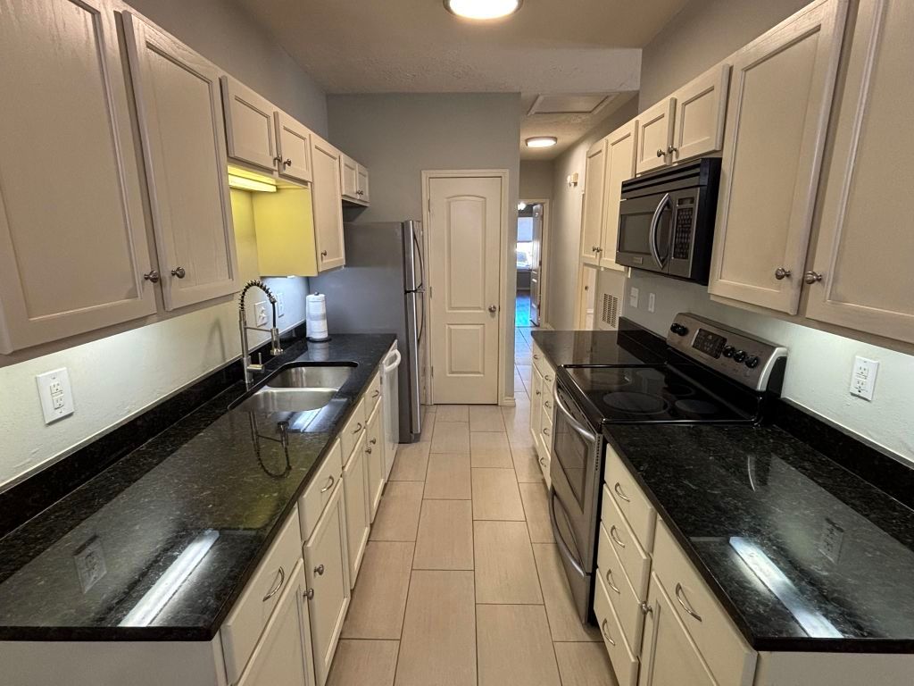 307 Quarry Street San Marcos, TX 78666 - Photo 14 of 38 Kitchen with stainless steel appliances, dark stone counters, and light tile patterned flooring