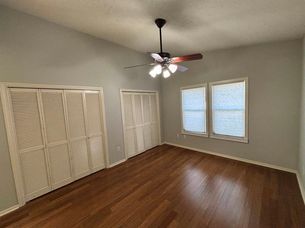307 Quarry Street San Marcos, TX 78666 - Photo 18 of 38 Unfurnished bedroom featuring multiple closets, dark wood-style floors, a ceiling fan, and a textured ceiling