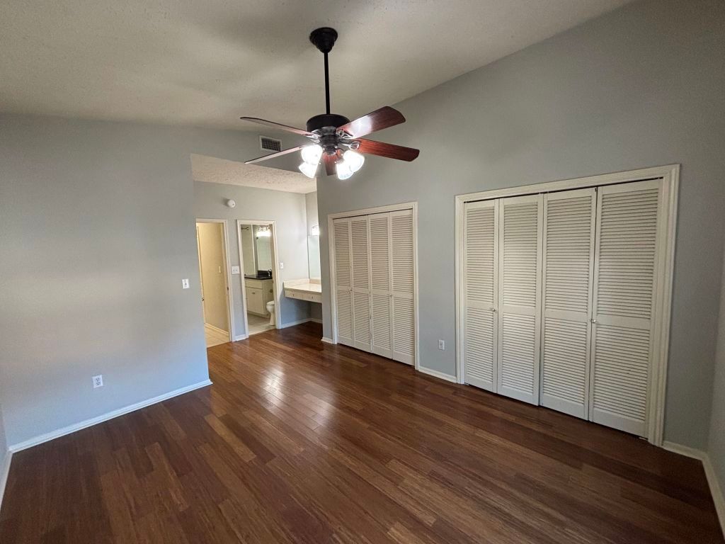 307 Quarry Street San Marcos, TX 78666 - Photo 21 of 38 Unfurnished bedroom featuring multiple closets, dark wood finished floors, ceiling fan, vaulted ceiling, and ensuite bathroom