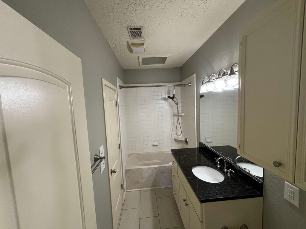 307 Quarry Street San Marcos, TX 78666 - Photo 25 of 38 Full bath featuring vanity, a textured ceiling, tub / shower combination, and light tile patterned floors