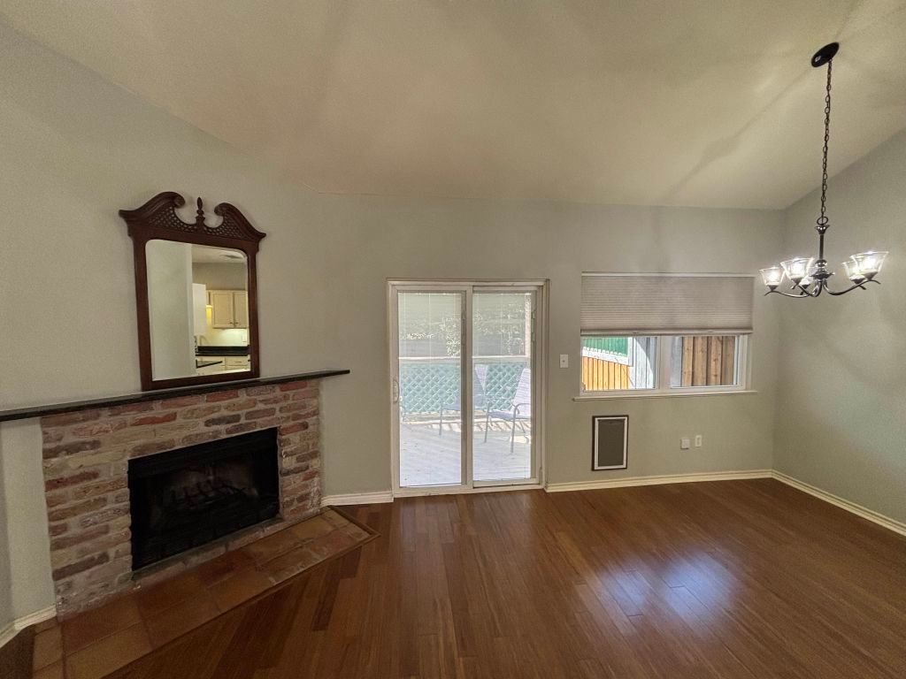 307 Quarry Street San Marcos, TX 78666 - Photo 3 of 38 Unfurnished living room with a chandelier, dark wood-style flooring, a fireplace, and lofted ceiling
