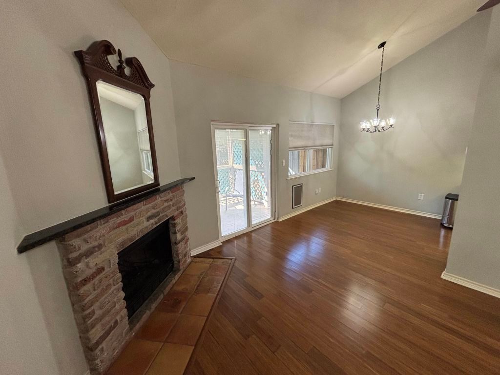 307 Quarry Street San Marcos, TX 78666 - Photo 4 of 38 Unfurnished living room featuring a brick fireplace, dark wood-type flooring, a chandelier, and high vaulted ceiling