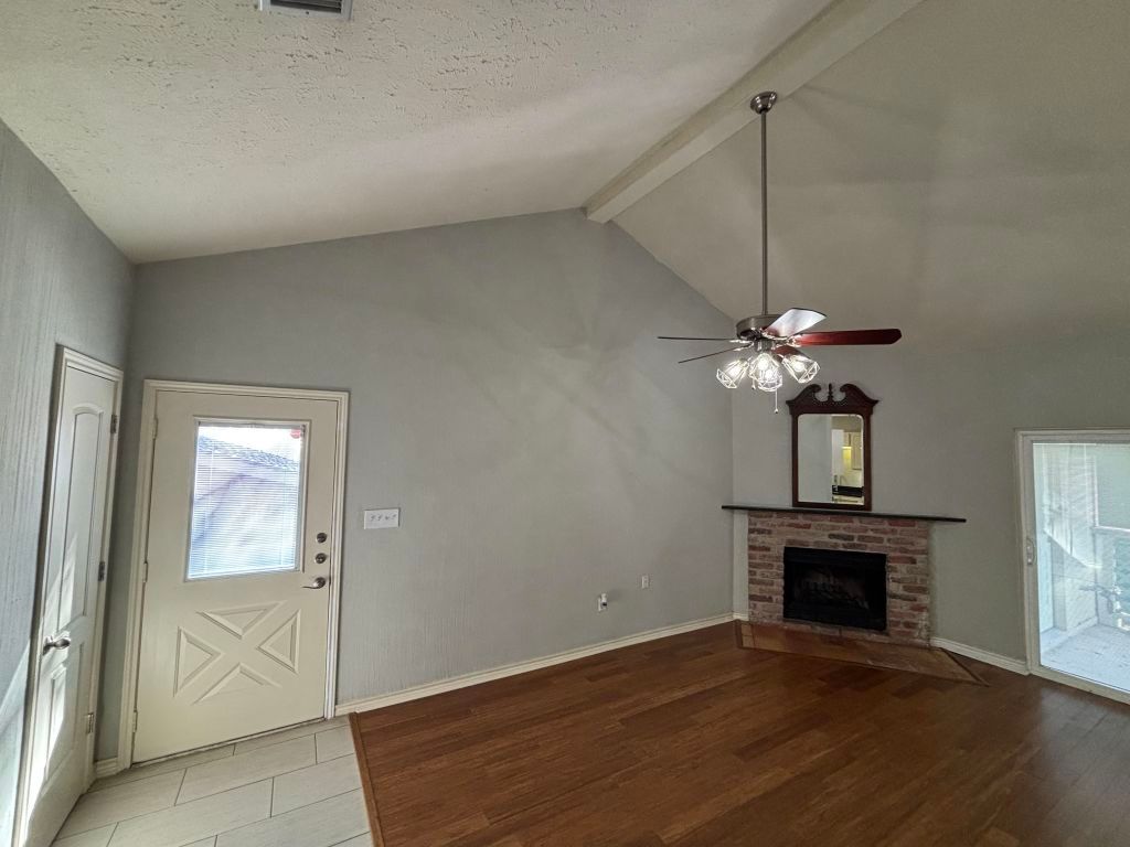 307 Quarry Street San Marcos, TX 78666 - Photo 8 of 38 Unfurnished living room featuring a fireplace, a textured ceiling, healthy amount of natural light, wood finished floors, and ceiling fan