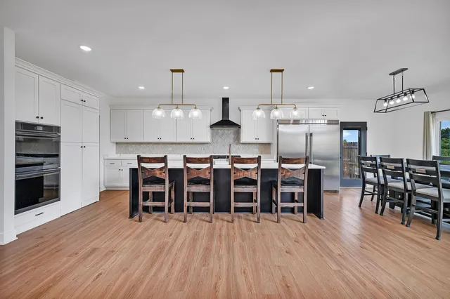 a kitchen with stainless steel appliances a dining table chairs stove and cabinets