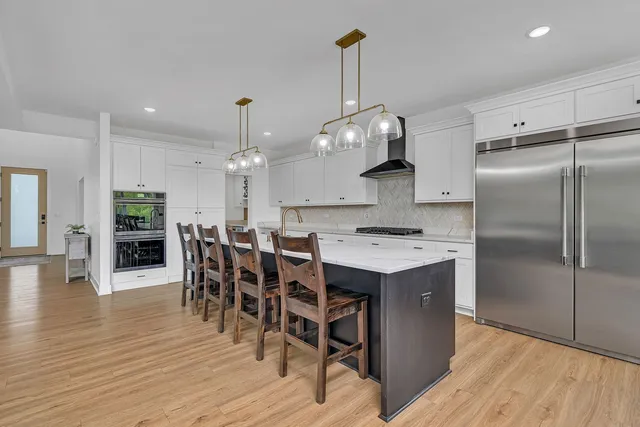 a kitchen with stainless steel appliances kitchen island a wooden floor and white cabinets