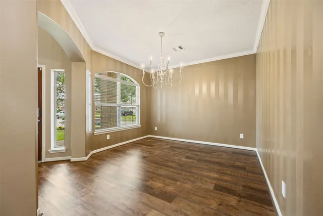 a view of an empty room with glass door and wooden floor