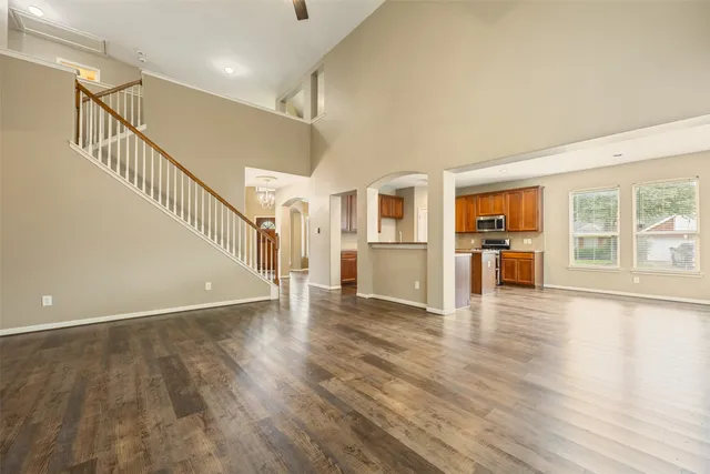 a view of empty room with wooden floor and a kitchen