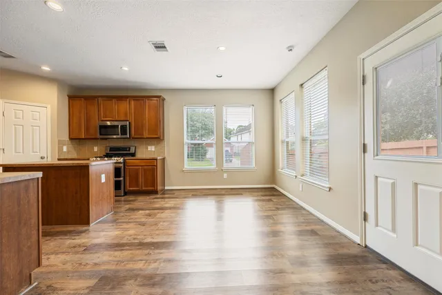 a large kitchen with granite countertop a stove a sink a refrigerator a window and a counter space