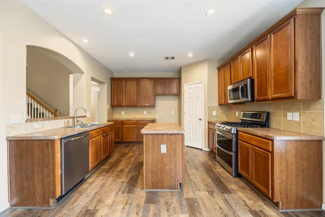 a large kitchen with stainless steel appliances granite countertop a stove a sink dishwasher and a refrigerator