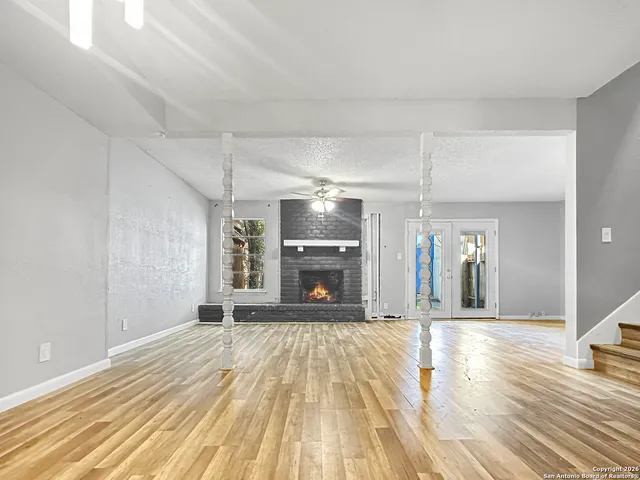 a view of an empty room with kitchen view and a fireplace
