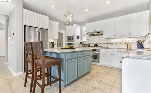a kitchen with stainless steel appliances granite countertop a table chairs sink refrigerator and cabinets