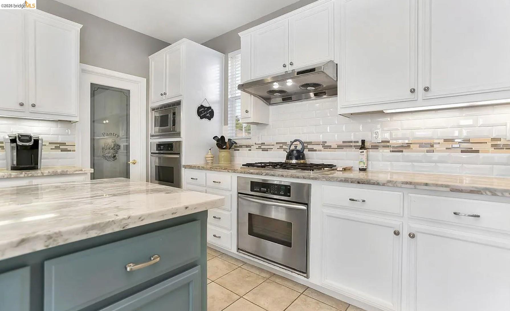 3251 Lookout Point Loop Discovery Bay, CA 94505 - Photo 4 of 31 Kitchen featuring light stone counters, stainless steel appliances, two tone cabinets, light tile patterned floors, and backsplash