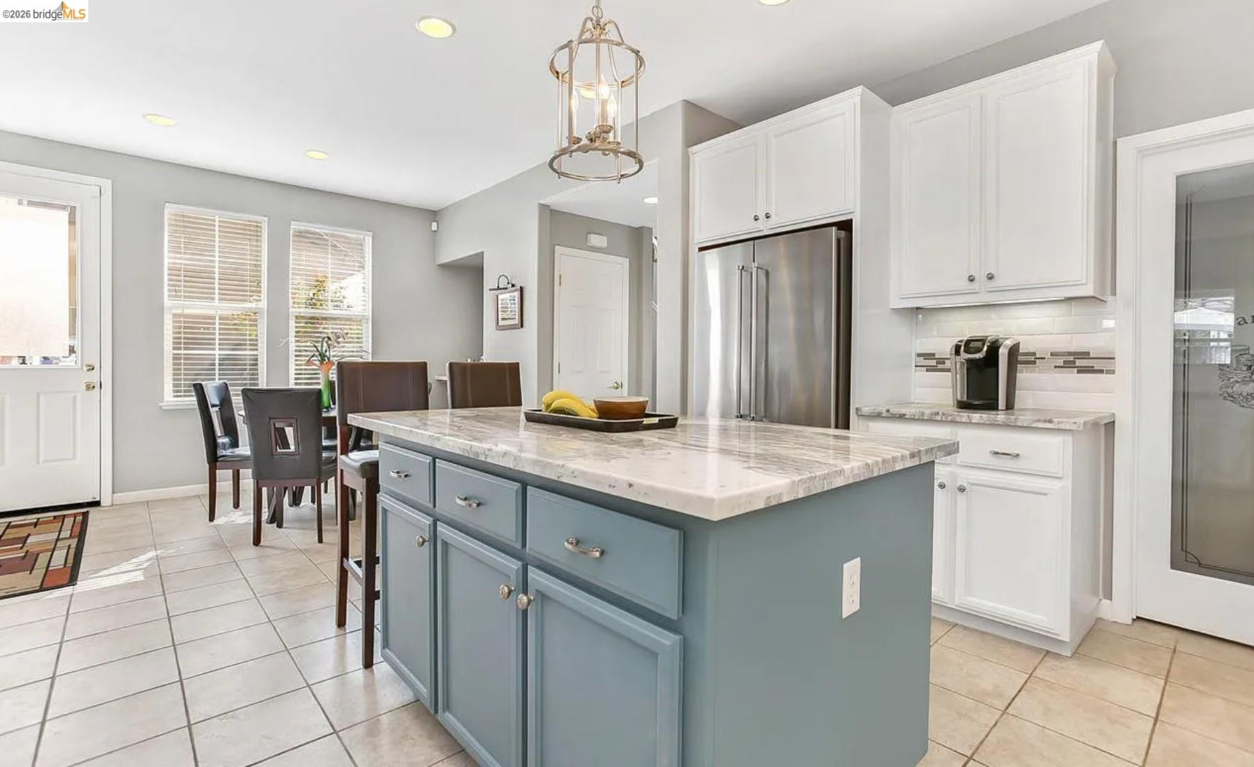3251 Lookout Point Loop Discovery Bay, CA 94505 - Photo 5 of 31 Two tone kitchen featuring light stone counters, high end refrigerator, decorative light fixtures, a center island, and light tile patterned flooring