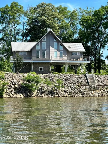 a view of a wooden house with large trees and playing area