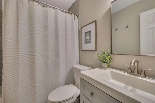 a bathroom with a granite countertop sink and a toilet
