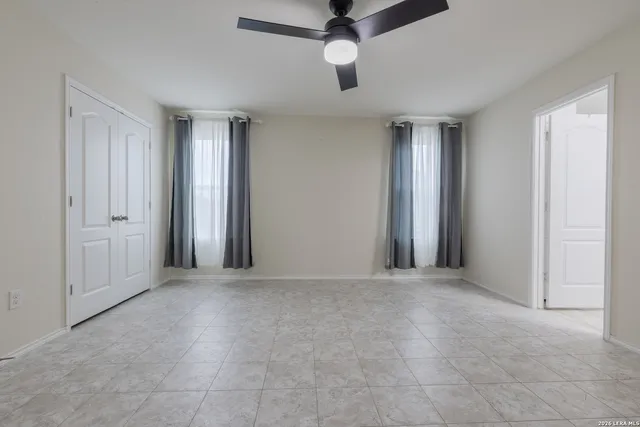 an empty room with ceiling fan and windows