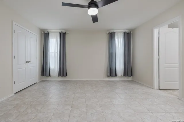an empty room with ceiling fan and windows
