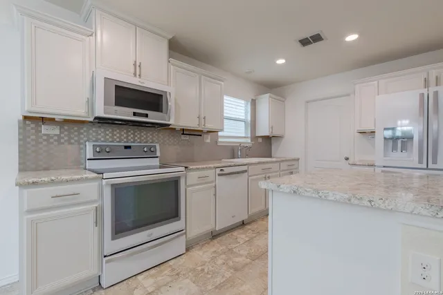 a kitchen with granite countertop white cabinets sink and stainless steel appliances