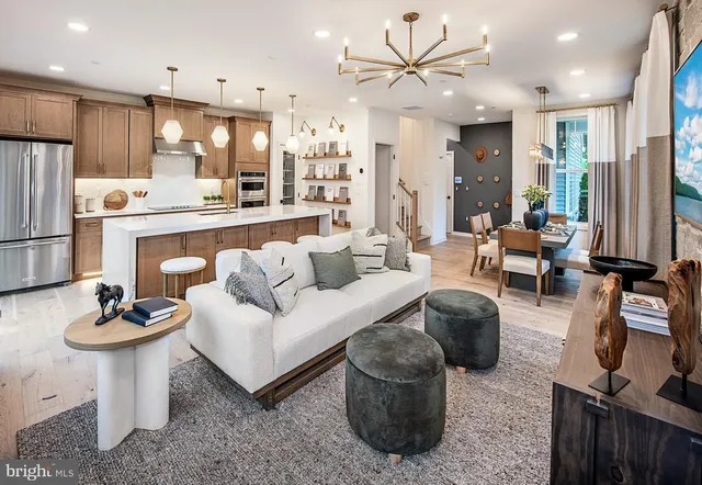 a living room with furniture a rug kitchen view and a chandelier