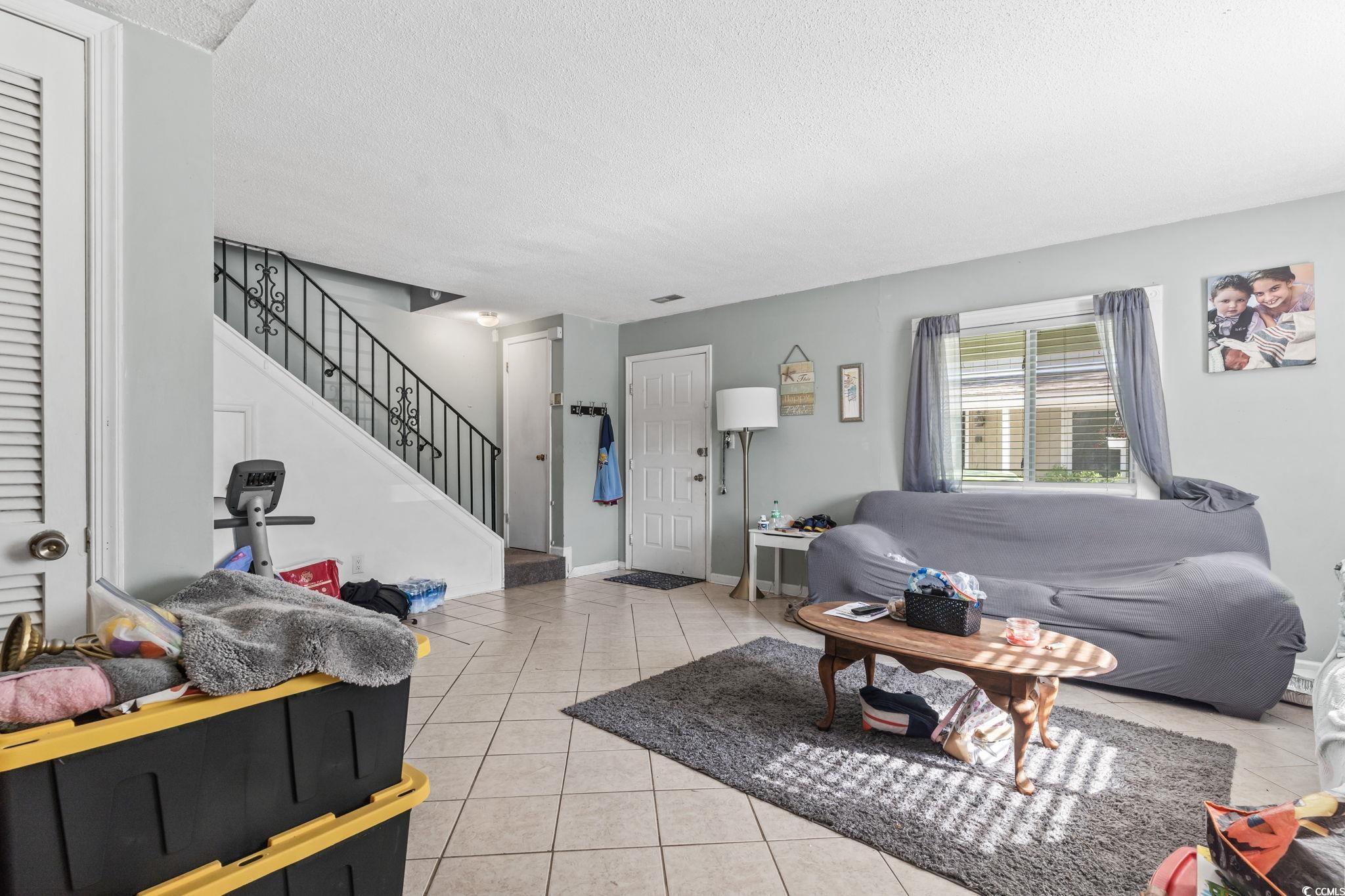 1411 Turkey Ridge Road, Unit 30B Surfside Beach, SC 29575 - Photo 3 of 21 Living area with stairway, baseboards, a textured ceiling, and light tile patterned floors