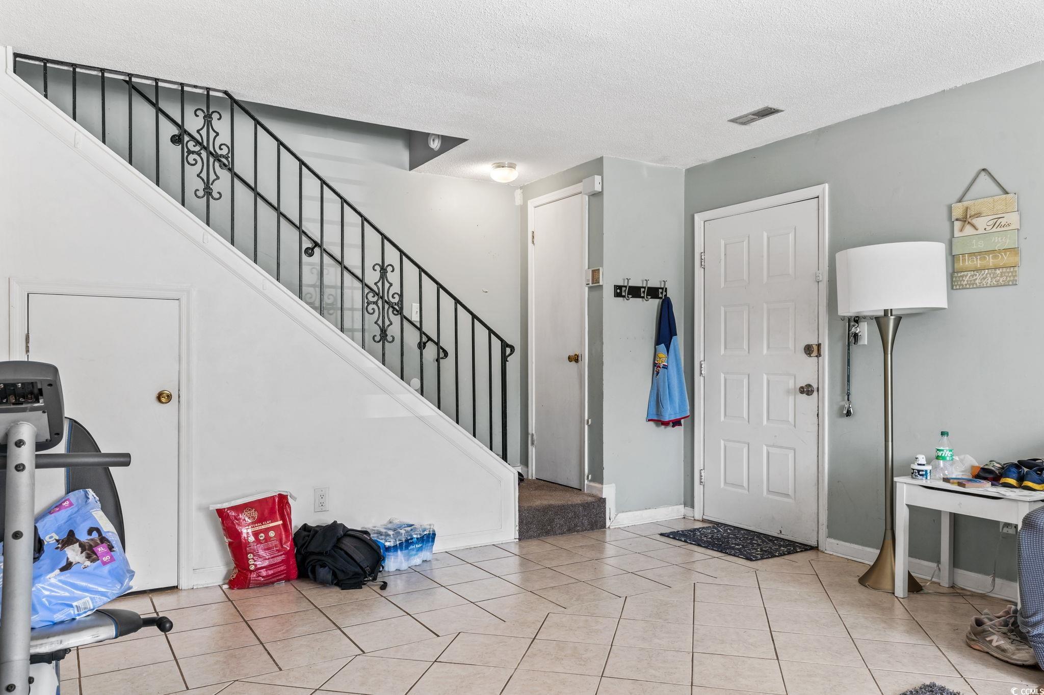 1411 Turkey Ridge Road, Unit 30B Surfside Beach, SC 29575 - Photo 4 of 21 Foyer with stairs, tile patterned floors, a textured ceiling, baseboards, and visible vents