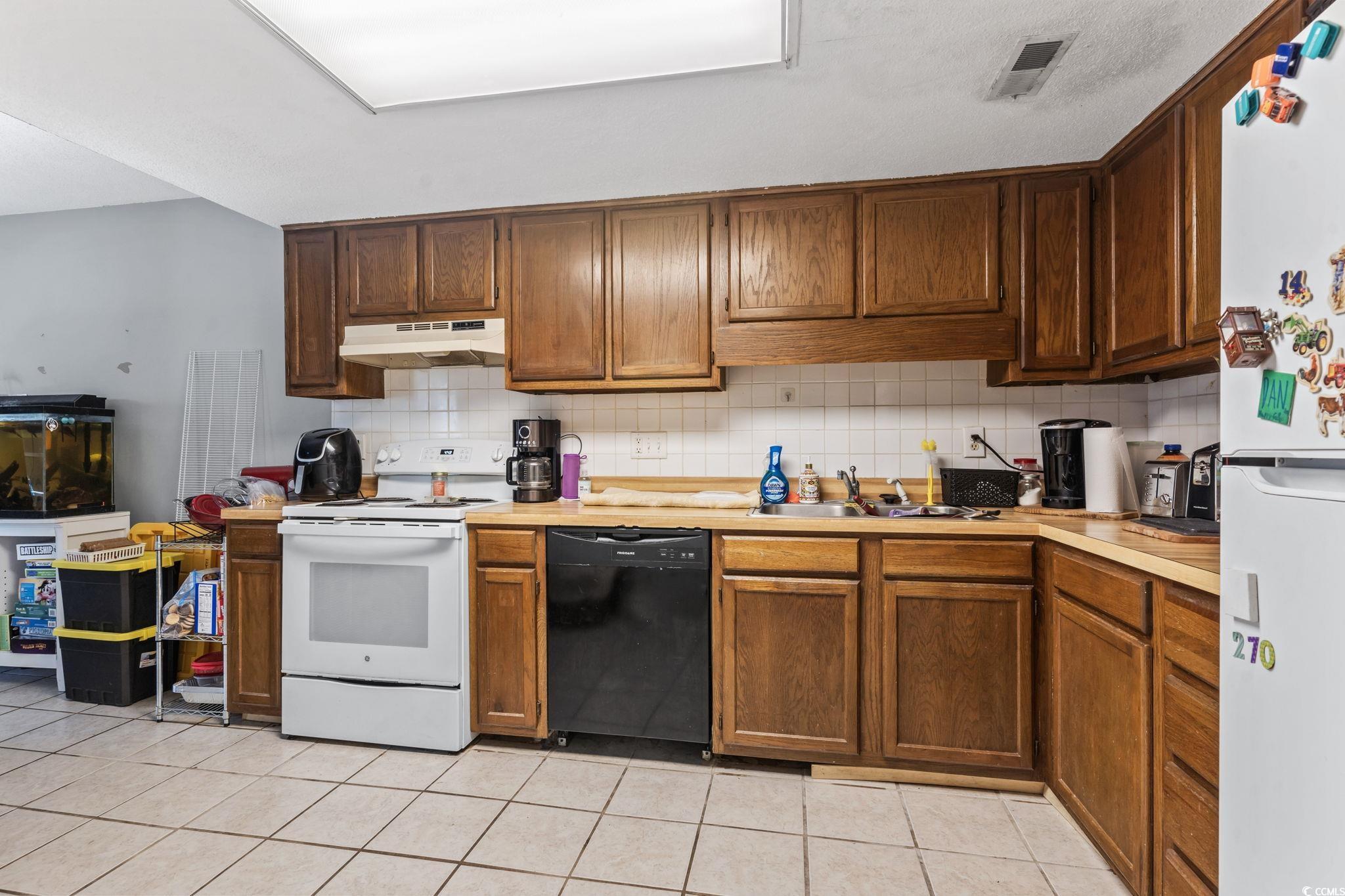 1411 Turkey Ridge Road, Unit 30B Surfside Beach, SC 29575 - Photo 6 of 21 Kitchen with a sink, decorative backsplash, white appliances, light countertops, and under cabinet range hood