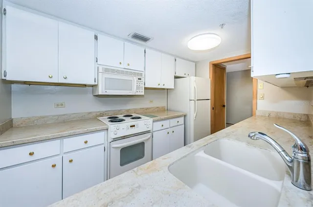 a kitchen with a white stove top oven sink and cabinets