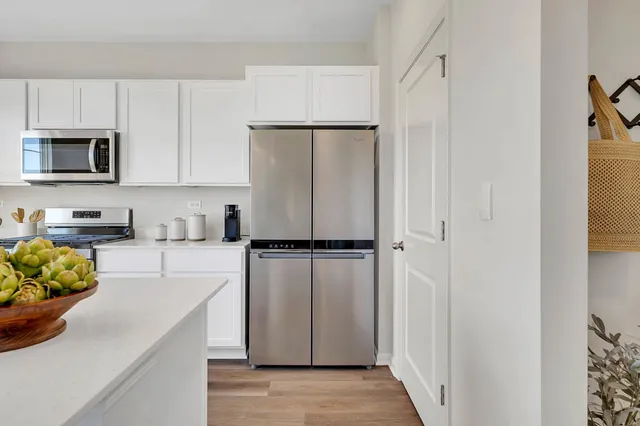 a kitchen with a refrigerator a stove and white cabinets