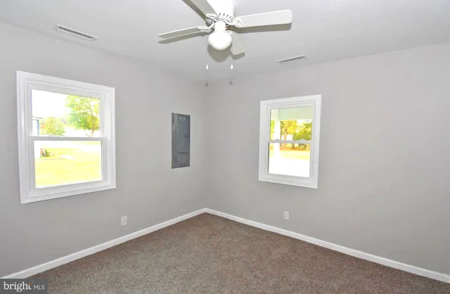 an empty room with windows and fan