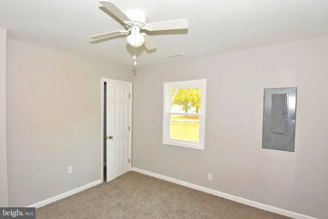 an empty room with a window and ceiling fan