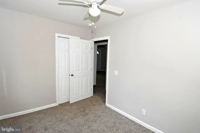 an empty room with a chandelier fan and closet area