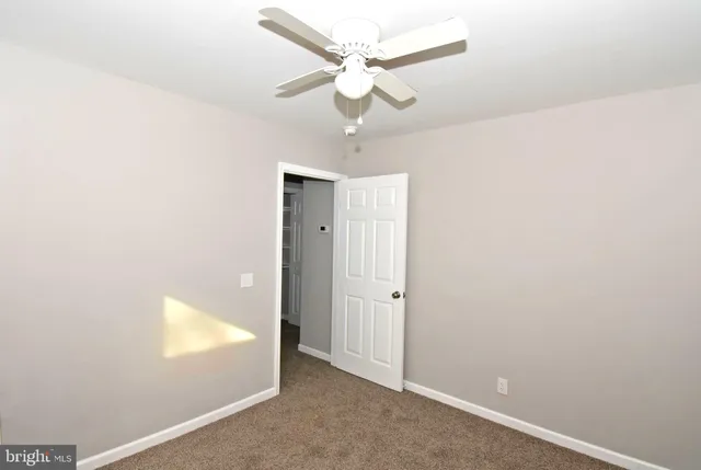 an empty room with a ceiling fan and a window