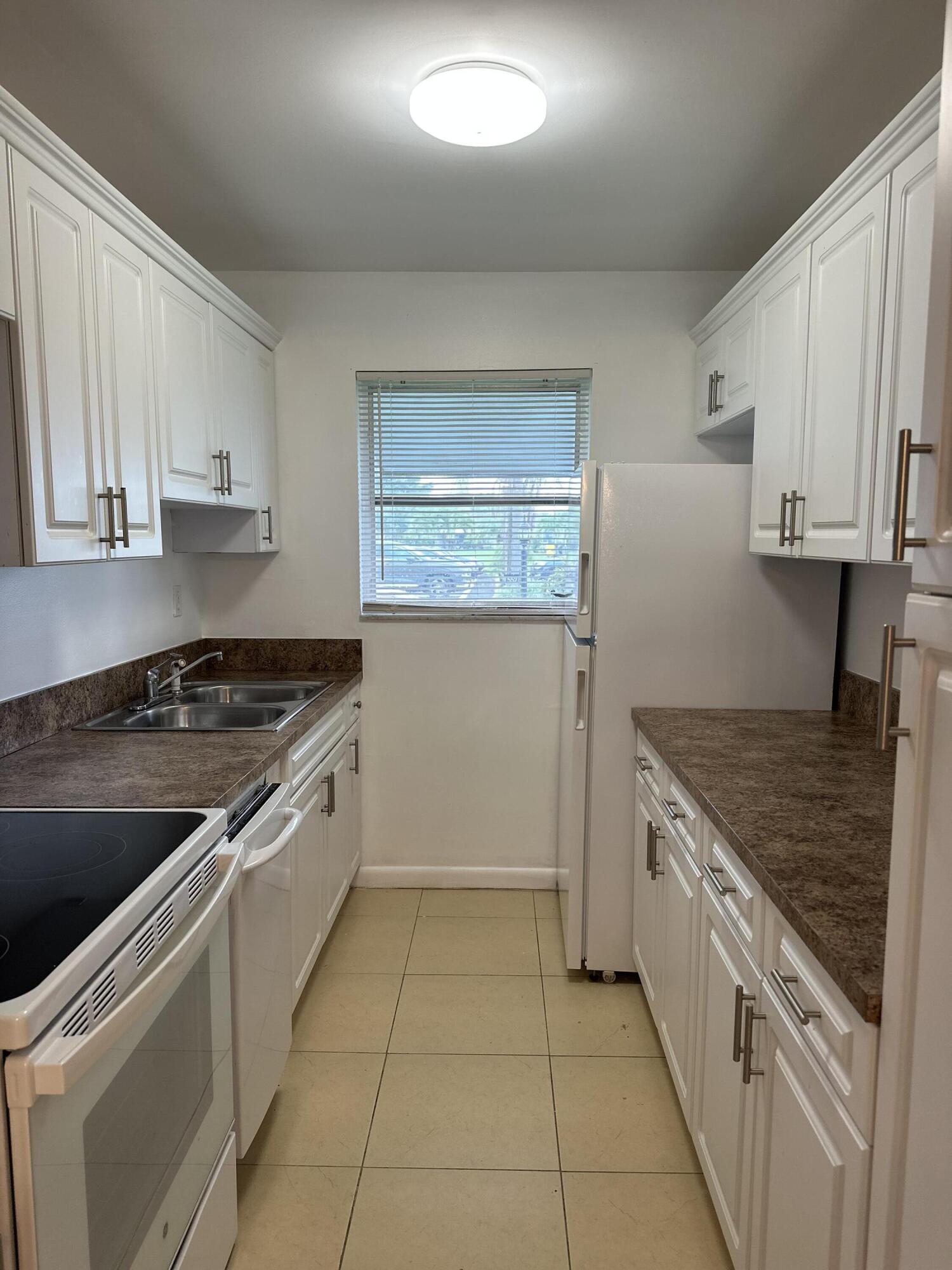 552 High Point Drive, Unit C Delray Beach, FL 33445 - Photo 5 of 13 a kitchen with a stove sink and cabinets