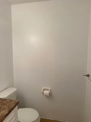 a bathroom with a granite countertop toilet and a sink