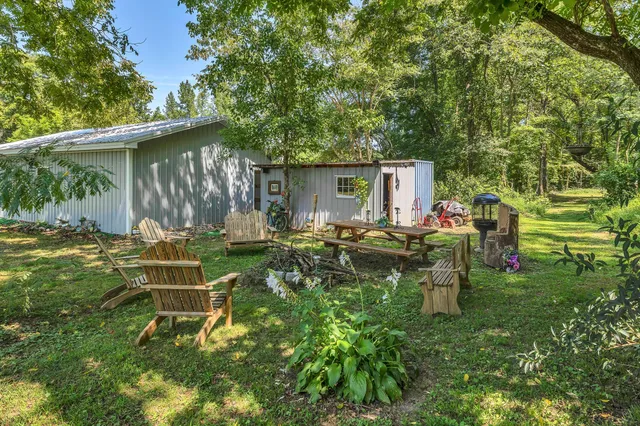 a view of backyard with table and chairs and a large tree