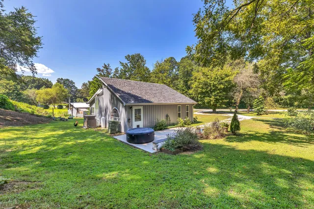 a view of a house with a big yard potted plants and large tree