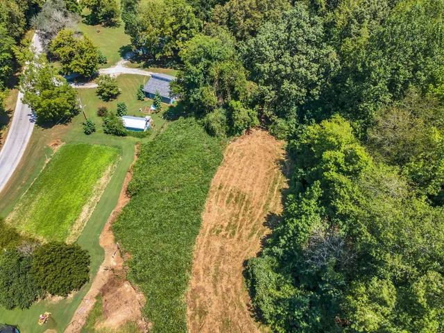 an aerial view of residential house with outdoor space and trees all around
