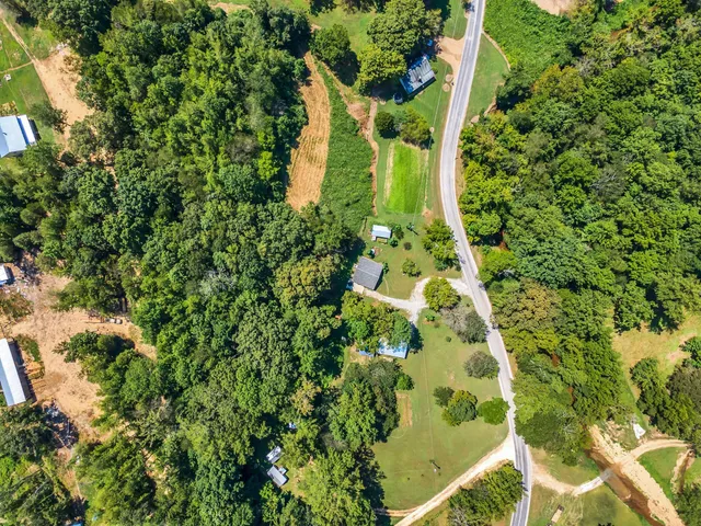 an aerial view of residential house with outdoor space and trees all around