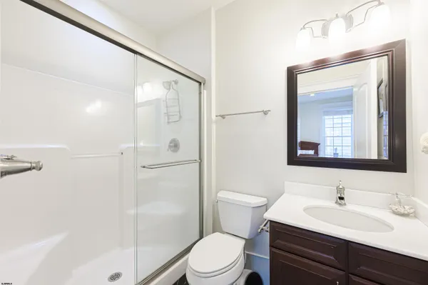 a bathroom with a toilet a sink a mirror a shower a vanity and window