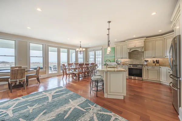 a kitchen with stainless steel appliances granite countertop a stove a refrigerator a kitchen island a stove and a wooden floors