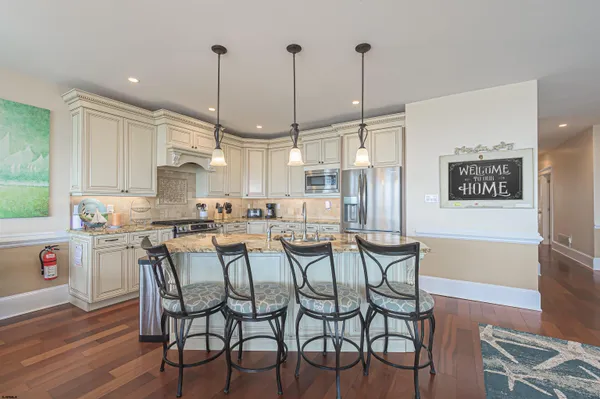 a kitchen with stainless steel appliances kitchen island granite countertop a dining table chairs and white cabinets