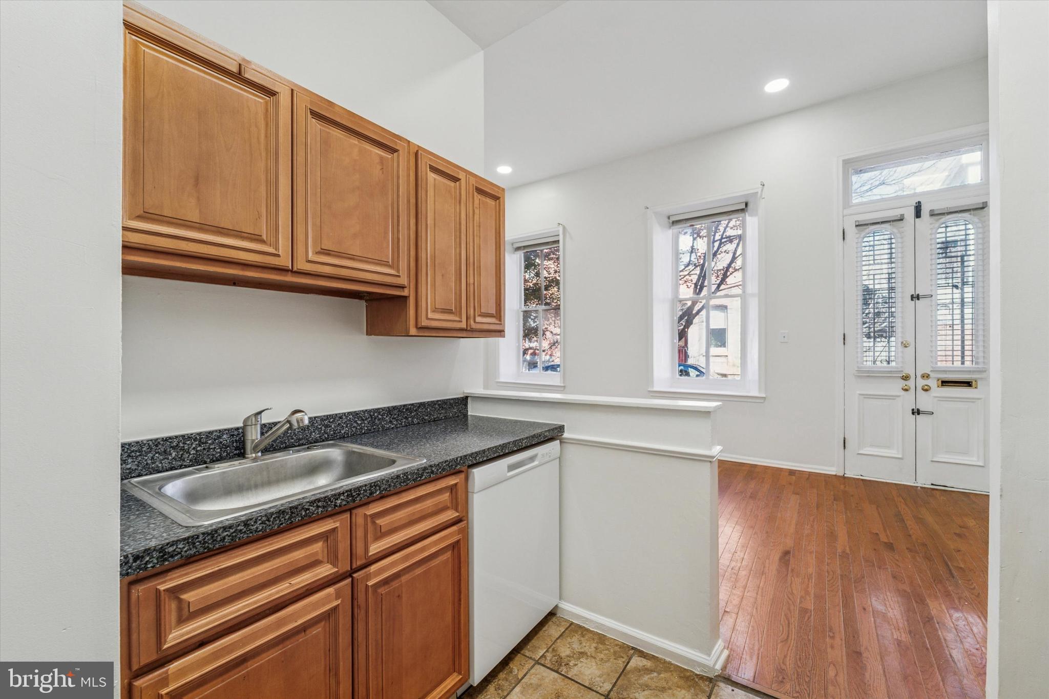 1606 Wallace Street, Unit 101 Philadelphia, PA 19130 - Photo 5 of 10 a kitchen with stainless steel appliances granite countertop a sink and cabinets with wooden floor