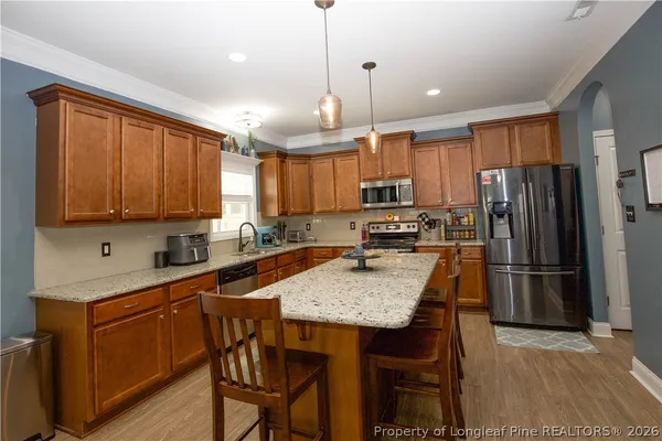 a kitchen with a refrigerator a stove a sink and chairs