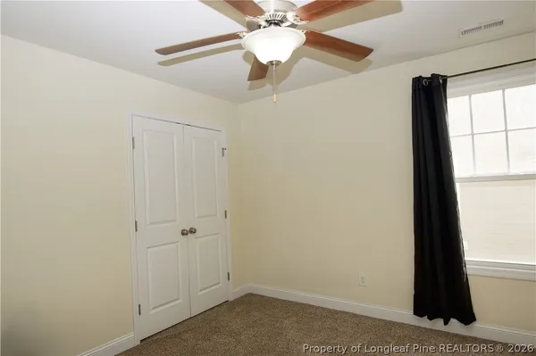 an empty room with a window and a ceiling fan