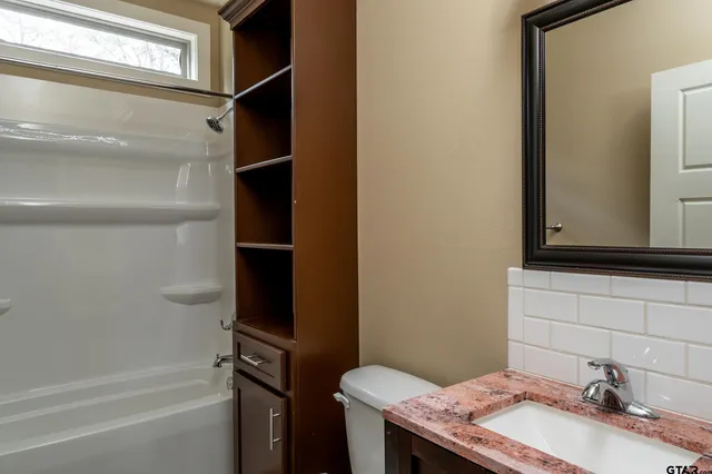 a bathroom with a granite countertop sink toilet and mirror
