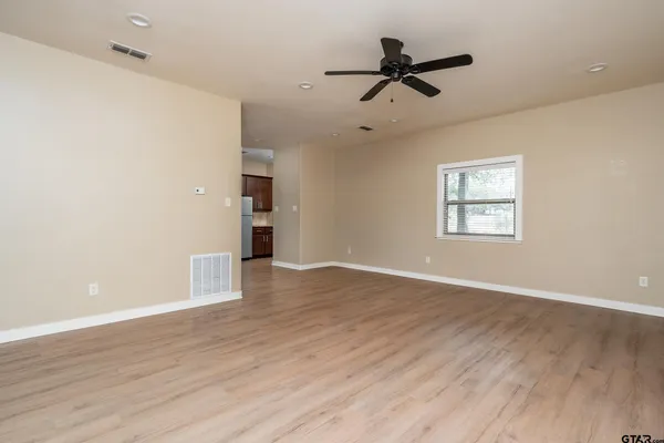 an empty room with wooden floor ceiling fan and windows