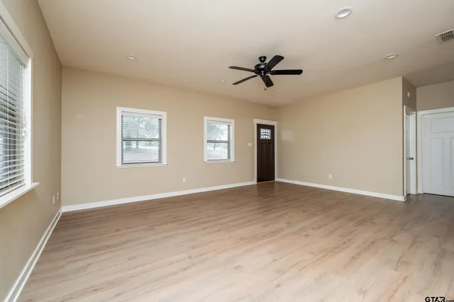 a view of empty room with wooden floor and fan